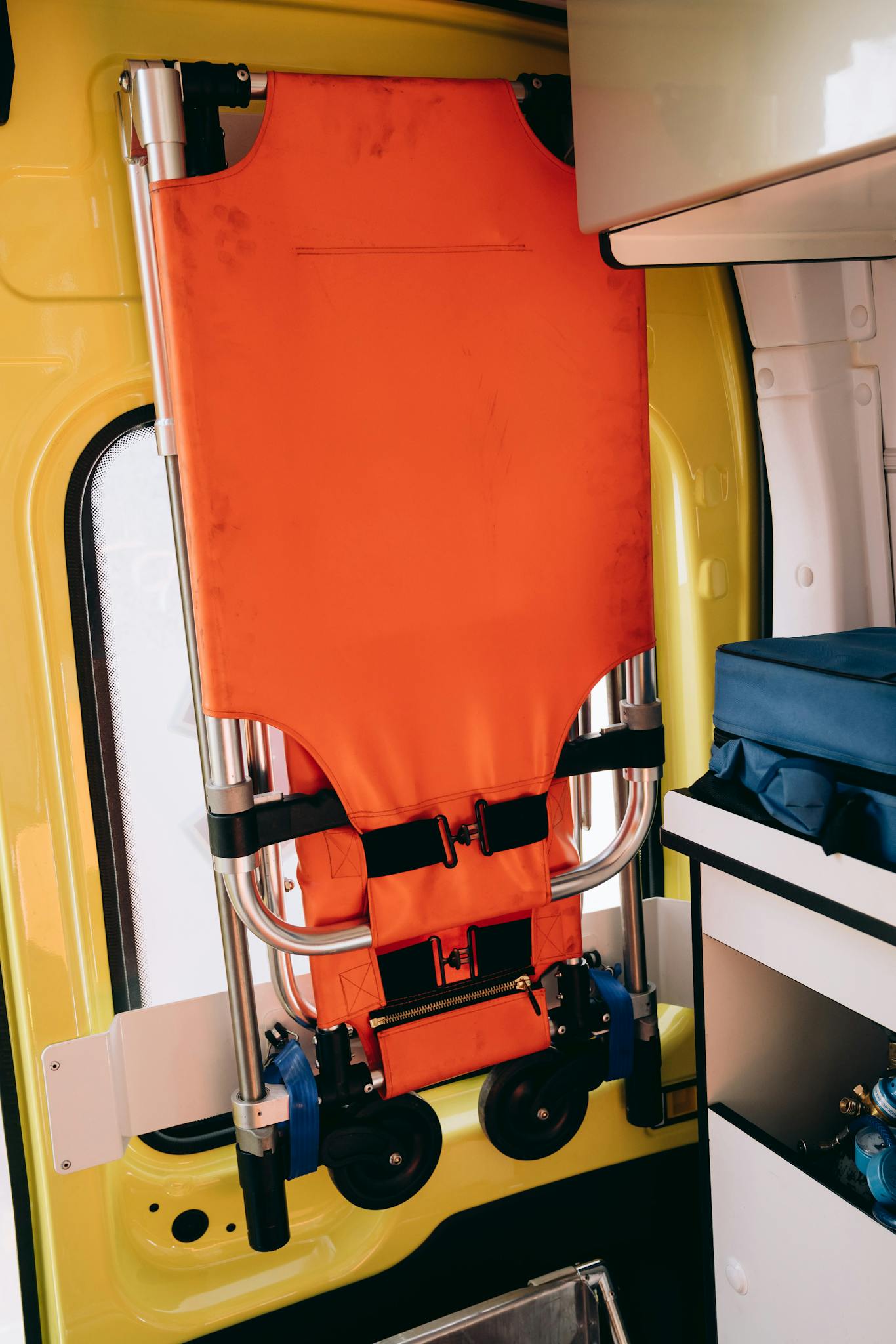 A folded orange stretcher is secured inside a modern ambulance for emergency response.