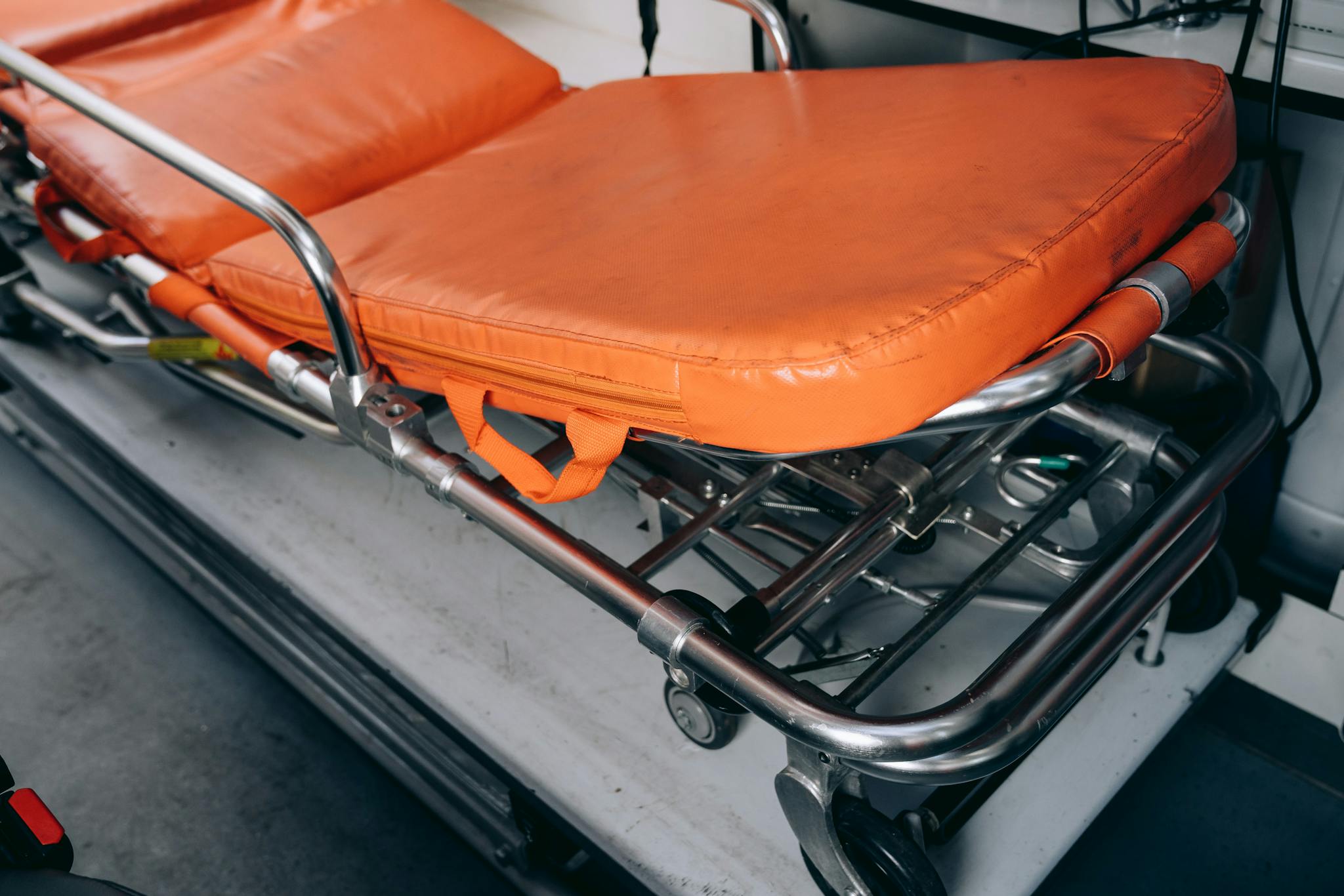 Close-up of an emergency medical stretcher used for patient transport with orange padding.
